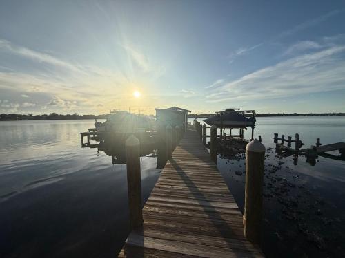 a dock on a body of water with the sun setting at Sandy Pines Perch - Your Indian River Dock Life Base Camp in Sebastian