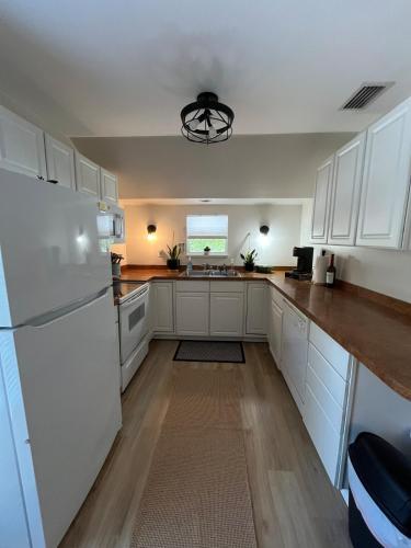 a kitchen with white cabinets and a white refrigerator at Sandy Pines Perch - Your Indian River Dock Life Base Camp in Sebastian