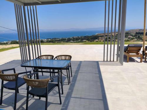 a table and chairs on a patio with a view of the ocean at Thalori villa 2 in Psalidi