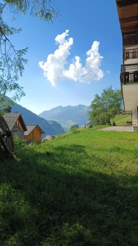 a grassy hill with a house and mountains in the background at Der Alpenfrieden in Marul