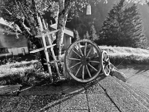 a wooden wagon wheel and a cross on the sidewalk at Der Alpenfrieden in Marul