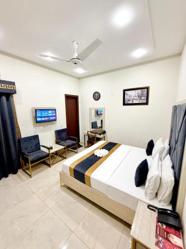 a bedroom with a bed and two chairs and a tv at Pakeeza Hotel - Faisal Town in Lahore