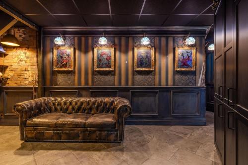 un canapé en cuir dans une pièce avec des tableaux au mur dans l'établissement Magic BNB Serris, 6pers, 5min Disneyland, à Serris