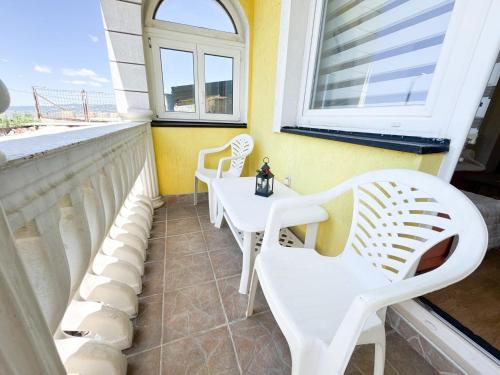a balcony with white chairs and a table and a window at InstaView Sarajevo - Private parking in Sarajevo