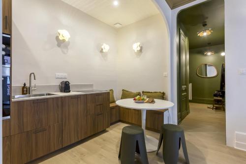 - une cuisine avec un évier, une table et des tabourets dans l'établissement Bosuites - 7 minutes du centre de Lyon, à Villeurbanne