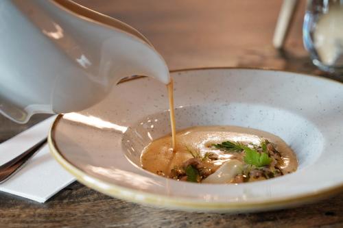 a bowl of soup with sauce being poured into it at Lighthouse Hotel & Spa in Büsum