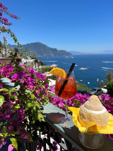 a drink on a table with a hat and flowers at Locanda Costa D'Amalfi in Amalfi