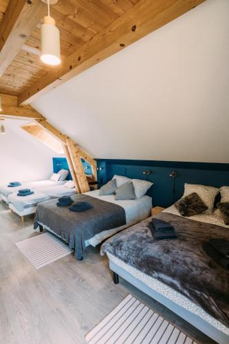 Cette chambre comprend 3 lits et un plafond en bois. dans l'établissement CHALET LA FOUGERE 15 personnes 180m2 bauges Savoie Thoiry, à Thoiry