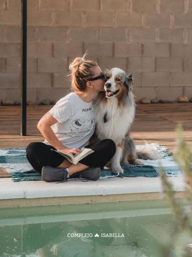 a woman sitting on the edge of a pool with a dog at COMPLEJO ISABELLA in Villa Amancay