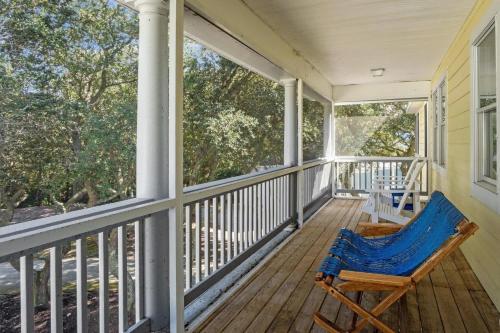 a rocking chair on a porch with a view of trees at Limoncello Grove Formerly Moondance in Corolla