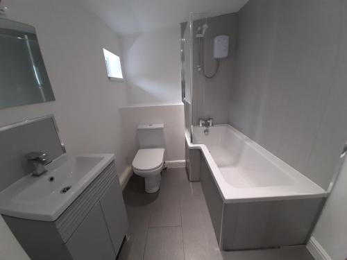 a white bathroom with a toilet and a tub and a sink at Bright & Comfy 3-Bedroom Flat in Kexgill in Middlesbrough