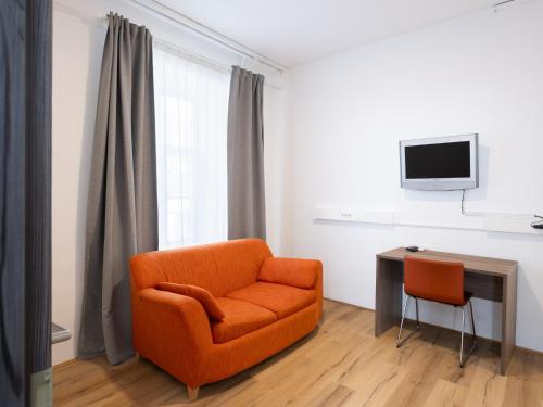 a living room with an orange chair and a desk at B&B HOTEL Maribor UNI Hostel in Maribor