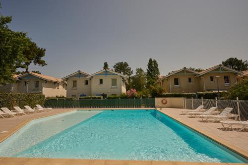 - une piscine avec des chaises et certaines maisons dans l'établissement Maison de vacances avec piscine, à 2 pas de l'océan Atlantique, au Le Verdon-sur-Mer