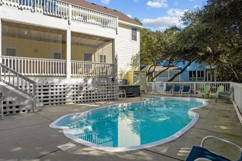 a swimming pool in a yard next to a house at Limoncello Grove Formerly Moondance in Corolla