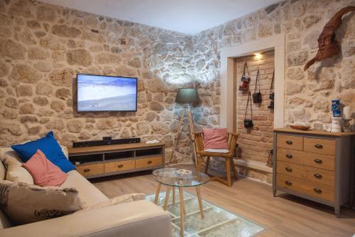 - un salon avec un canapé et une télévision sur un mur en pierre dans l'établissement Villa Toni, à Tučepi