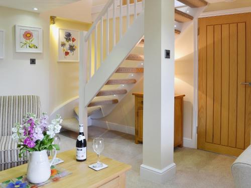 a living room with stairs and flowers on a table at Dairy Cottage in Matfield