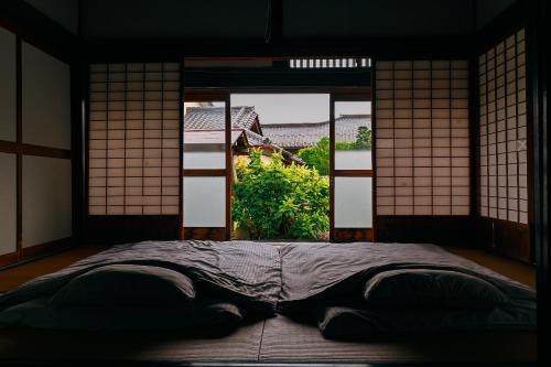 a bed in a room with an open window at THE Aramaki 日本の魅力と伝統が詰まった築200年の古民家 1日1組限定貸切 in Ō-naka
