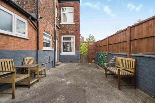 two wooden benches sitting outside of a brick building at GuestReady - Charming Home in Vibrant Levenshulme in Manchester