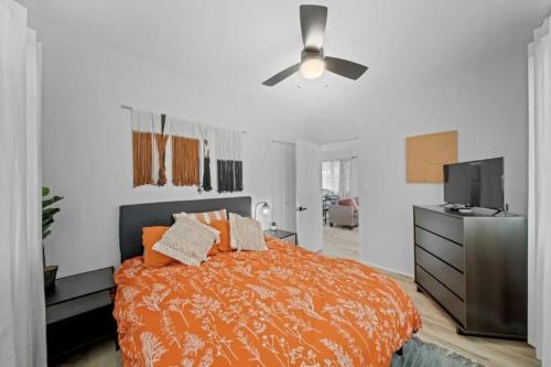 Cette chambre comprend un lit avec des draps orange et un ventilateur de plafond. dans l'établissement Tropical Haven - 2BR Hilo, à Hilo
