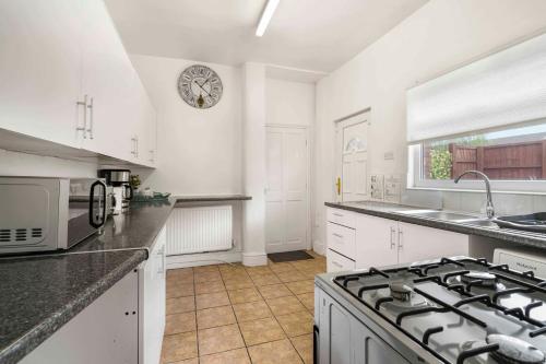 a kitchen with white cabinets and a clock on the wall at GuestReady - Charming Home in Vibrant Levenshulme in Manchester
