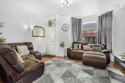 a living room with a couch and chairs and a clock at GuestReady - Charming Home in Vibrant Levenshulme in Manchester