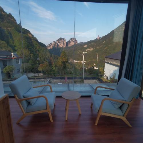 a room with two chairs and a table and mountains at Cloud House Of Leisurely in Zhangjiajie
