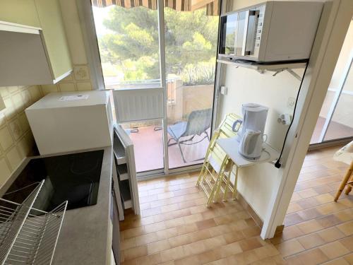 une cuisine avec un réfrigérateur, une table et une fenêtre dans l'établissement T1 climatisé avec parking à 700m des plages, animaux admis - FR-1-316-250, à Le Brusc