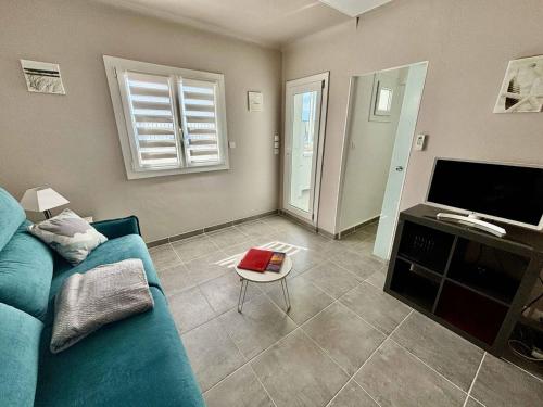 un salon avec un canapé bleu et une télévision dans l'établissement Appartement sur l'eau avec clim, plage privée - FR-1-816-5, au Lavandou