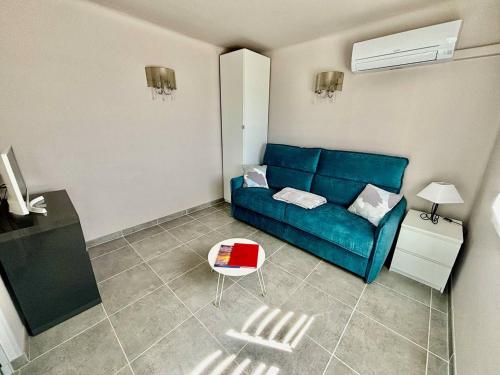 un salon avec un canapé bleu et une table dans l'établissement Appartement sur l'eau avec clim, plage privée - FR-1-816-5, au Lavandou