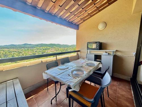 une salle à manger avec une table et des chaises sur un balcon dans l'établissement Appartement rénové : Clim, Piscine et Vue Mer - FR-1-816-28, à Bormes-les-Mimosas