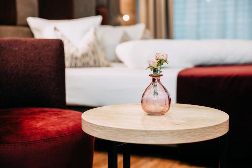 a vase with flowers on a table in a living room at Hotel Gasthof Zum Schwanen in Reutte