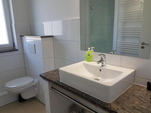 Un baño blanco con lavabo e inodoro. en dat geele hus Wohnung 6, en Büsum