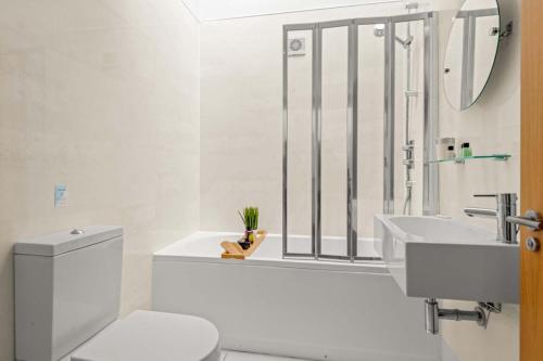 a white bathroom with a toilet and a sink at House 3 in Looe