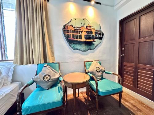 a room with two chairs and a table with a boat on the wall at 26 Rangoon Residence 26 in George Town