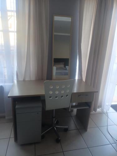 a desk with a mirror and a chair in a room at Home Sweet Home in Polokwane