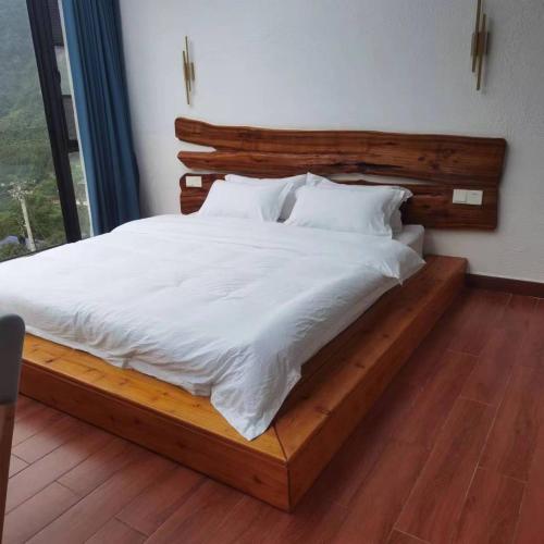 a bedroom with a wooden bed with white sheets at Cloud House Of Leisurely in Zhangjiajie
