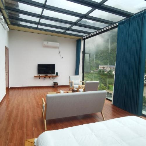 a living room with a tv and a large window at Cloud House Of Leisurely in Zhangjiajie