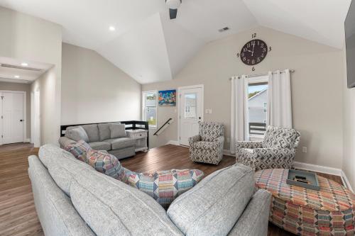 a living room with two couches and a clock on the wall at Masons Beach House Getaway in Kill Devil Hills