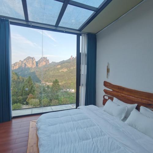 a bedroom with a bed and a large window at Cloud House Of Leisurely in Zhangjiajie