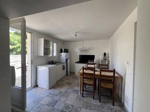 une cuisine avec une table, des chaises et un réfrigérateur dans l'établissement Chaleureuse maisonnette au cœur de Ruoms avec terrasse et parking - FR-1-697-35, à Ruoms