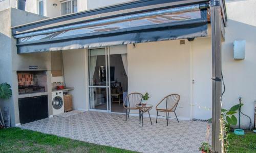 awning over a patio with two chairs and a table at Chito House in Buenos Aires