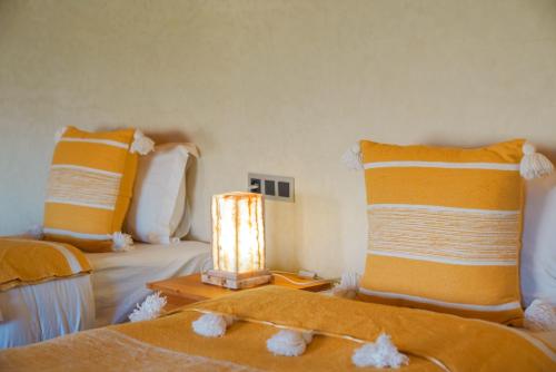 a bedroom with two beds with orange and white pillows at Kasbah Hnini in Igdourane