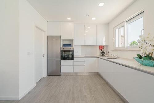 a kitchen with white cabinets and a large window at Casa Ventosa with private pool in Mariquiteira