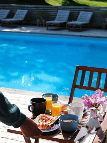 a table with breakfast foods and drinks on a table by a pool at Ljusterö Logi in Norra Ljustero