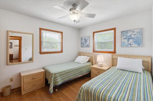 a bedroom with two beds and a ceiling fan at A Change In Attitude in Duck