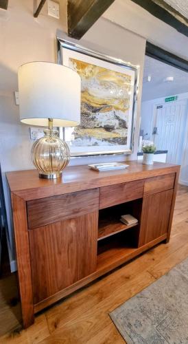 a lamp on top of a wooden entertainment center at Cosy Cottage in Harvington in Harvington