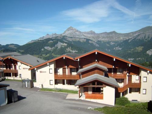 un grand bâtiment avec des montagnes en arrière-plan dans l'établissement Studio 4 pers. près des pistes, tout équipé - FR-1-733-161, à Crest-Voland