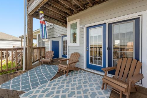 a porch with two chairs and a blue door at A Joyful Sound in Manteo