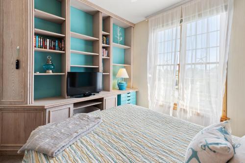 a bedroom with a bed and a tv and a window at A Joyful Sound in Manteo