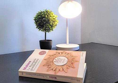 a book on a table with a lamp and a potted plant at Le Gentil 'Home - Hypercentre - proche Cathédrale in Évreux